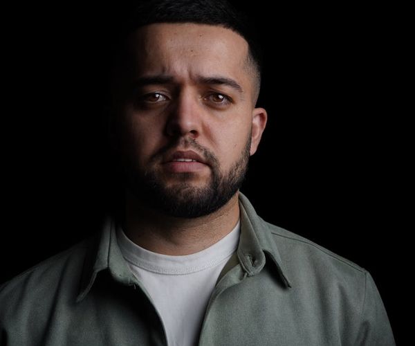 Silhouette of a man in a meditative pose against a dark, textured background.
